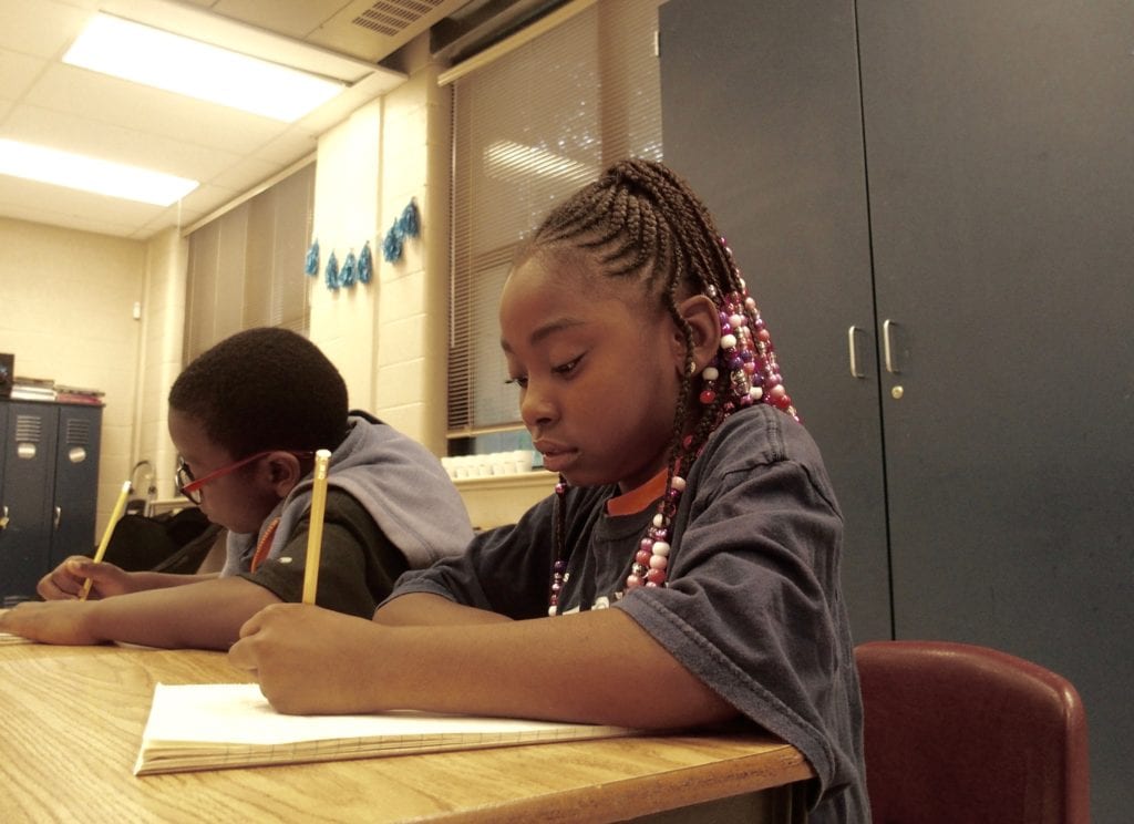 Third-grader Kenyari Harmon, 8, writes a story about her favorite athlete during the Read to be Ready literacy camp held at Cornerstone Prep in Memphis' Frayser neighborhood. June 27, 2019.